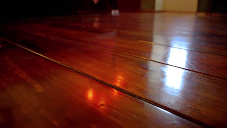 Waxed-dark-wood-beam-floor-lit-by-incandescent-lights,-Dolly-right-shot