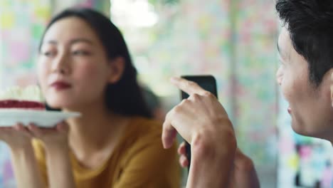 Handheld-view-of-Vietnamese-couple-using-mobile-phone-at-cafe