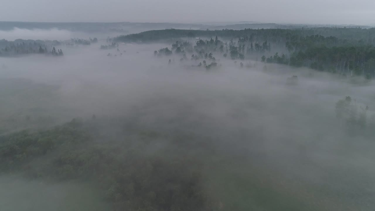 Low visibility aerial view flying through fog and smoke to reveal an Alberta country farm location