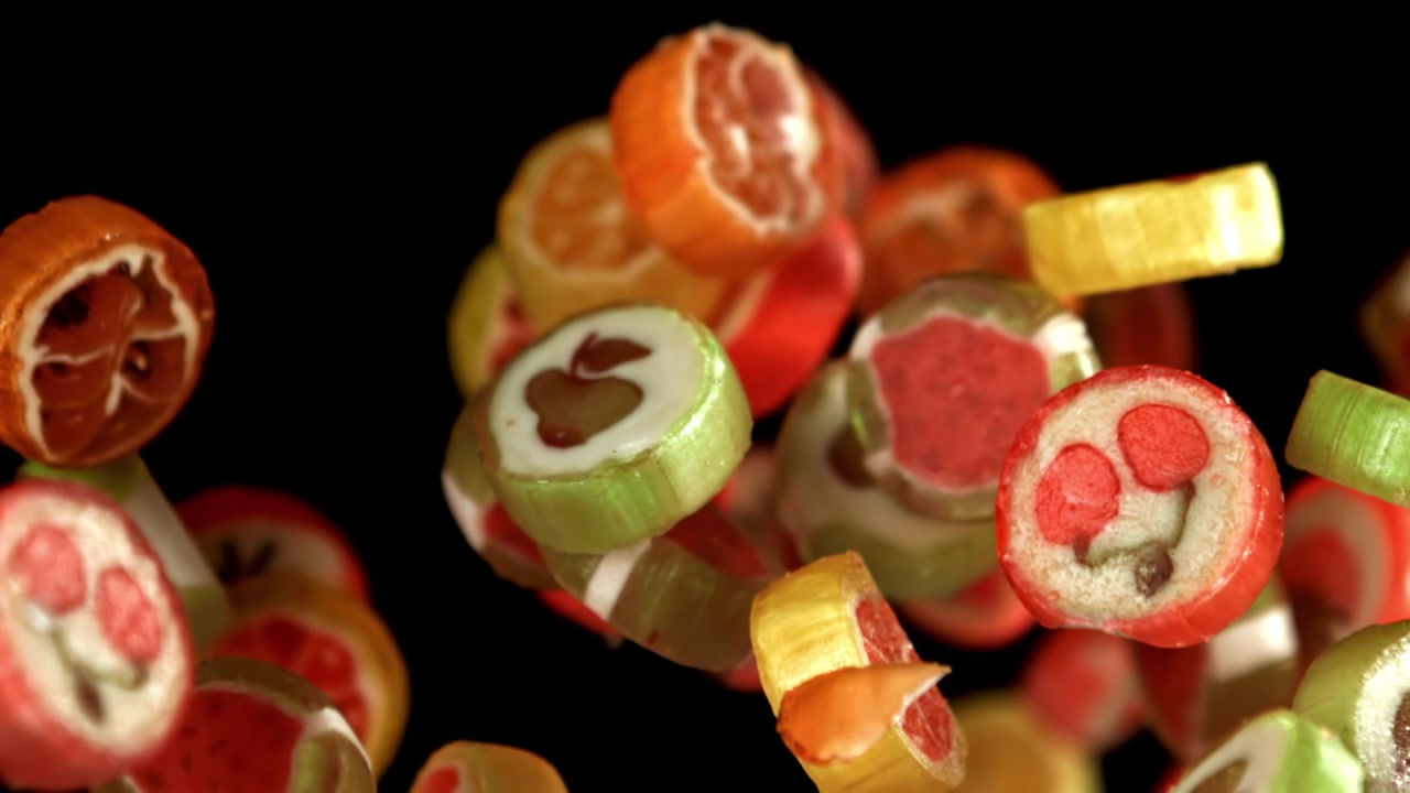 Bunte Fruchtbonbons fallen und schweben in Zeitlupe.