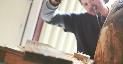 young carpenter shaping wood with chisel