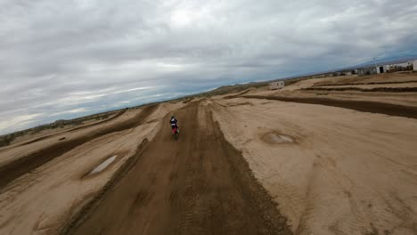 atleta de motocross salta una motocicleta sobre una pista de tierra en el desierto de mojave - vista aérea en cámara lenta