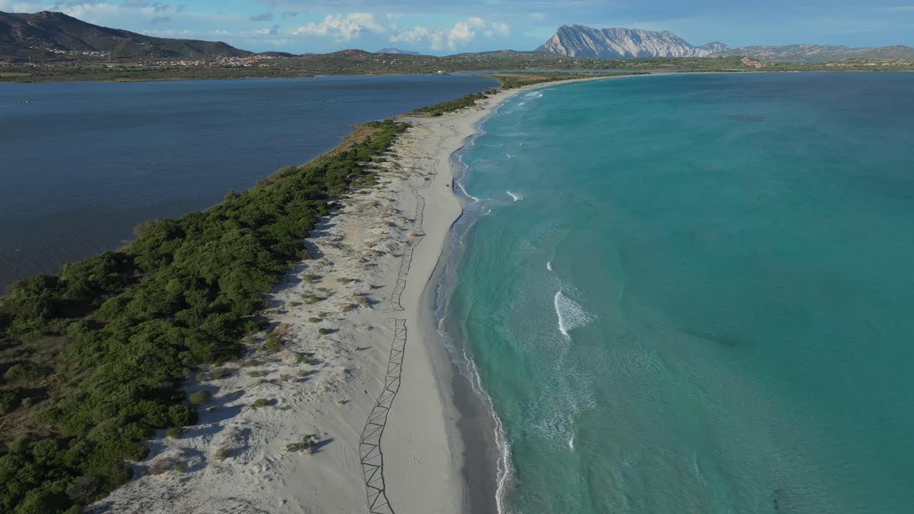 Turquoise waves gently caress the white sand of la cinta beach, sardinia, in this stunning aerial view