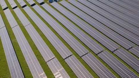 Tele-Lens-Slide-over-a-huge-solar-power-plant-with-multiple-solar-panels-on-a-green-hill-in-Germany,-Renewable-Energy,-Aerial-Footage