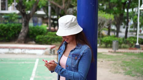 latin woman with hat using cell phone on street