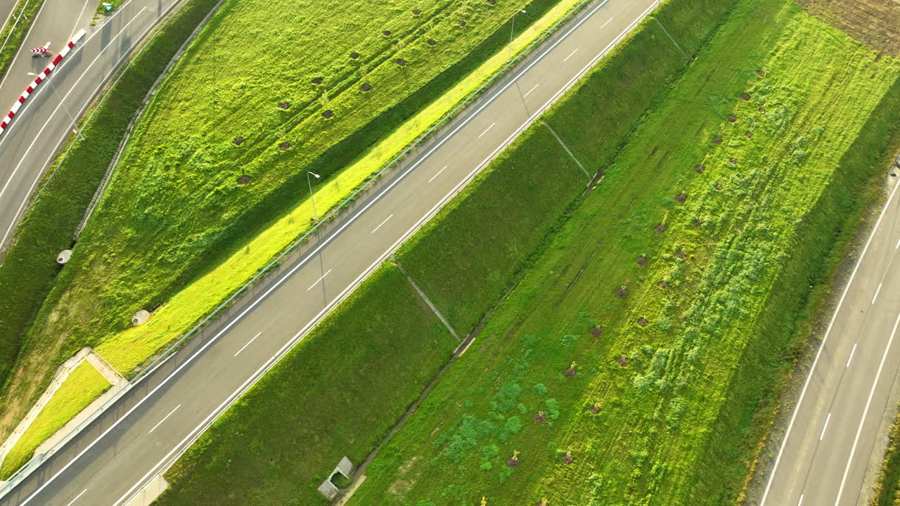 Drone view of sloping highway ramps and connecting roads surrounded by grass fields