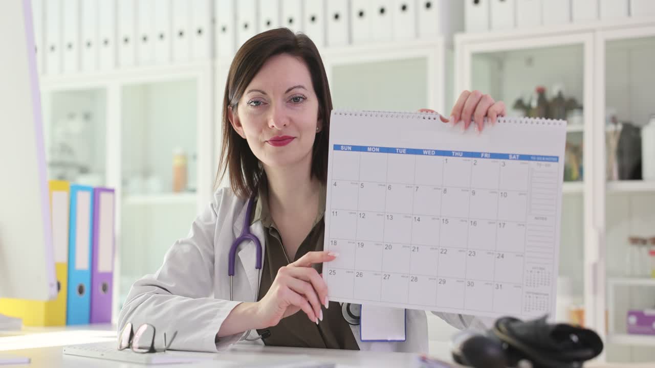 Female Doctor Holding Up a Calendar for Scheduling Appointments