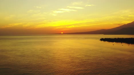 romantic aerial seascape, open ocean small island with mountains in the beautiful golden light of the sunset