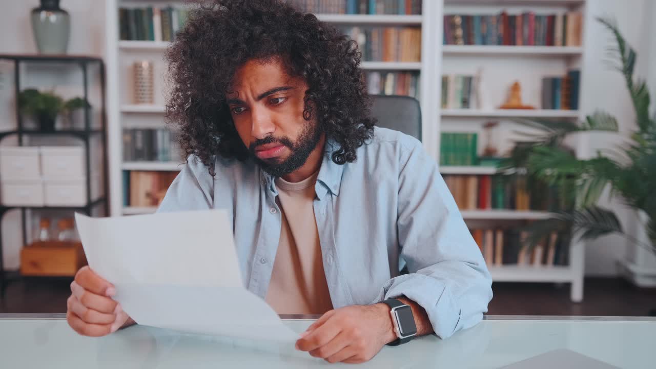 Young arabian man reads letter with unpleasant news sits in home office