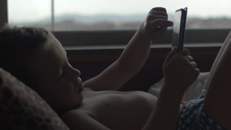 child using digital tablet in bed