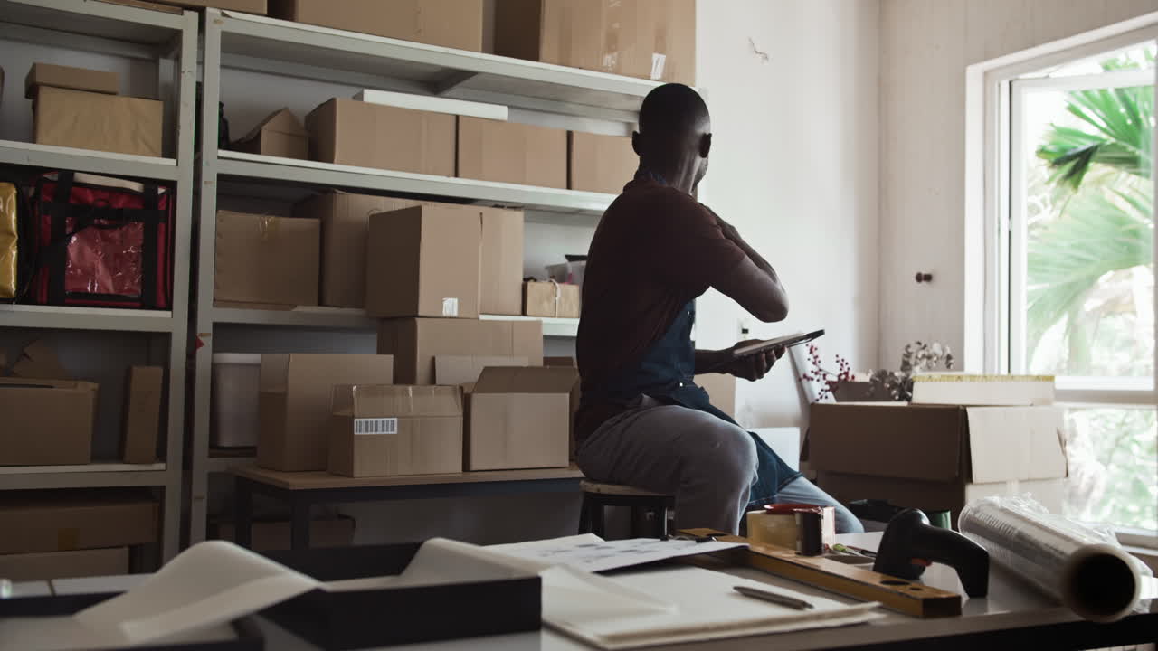 Black Storage Office Manager Entering Data about Parcels on Tablet