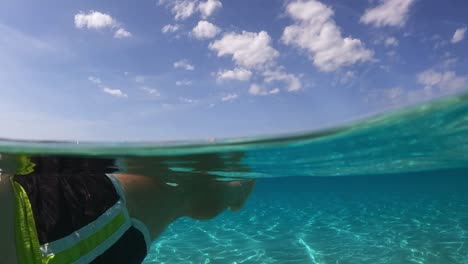 personal perspective of man legs and feet floating on beautiful clear and transparent sea water of turquoise lagoon on tropical island