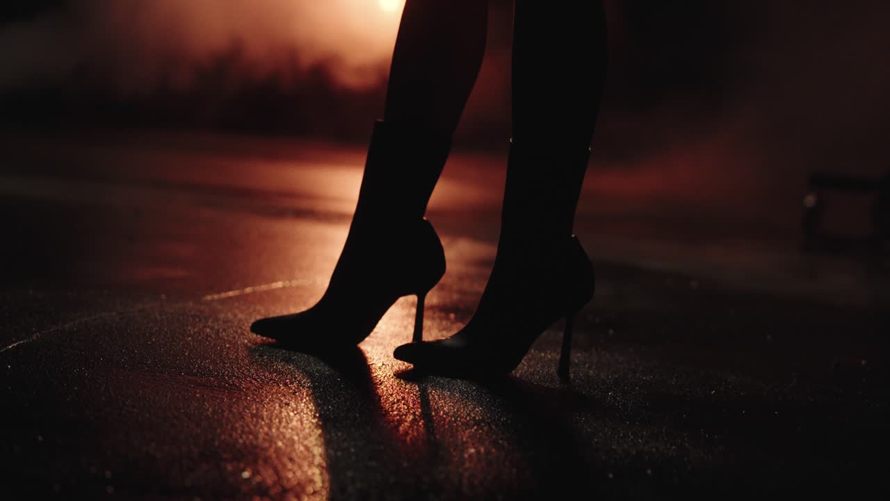black women's high heels with wet street. street reflected LEDs. in slow motion