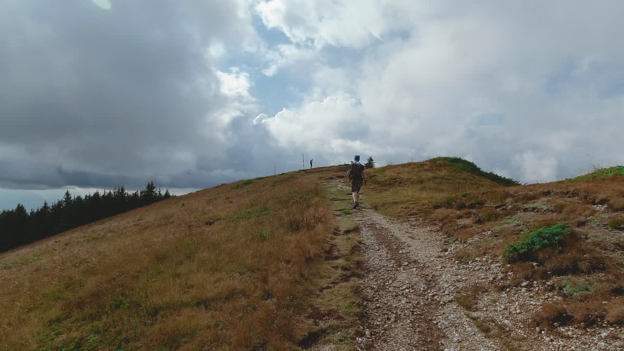 Following shot of a guy hiking through a trail toward the top of a mountain