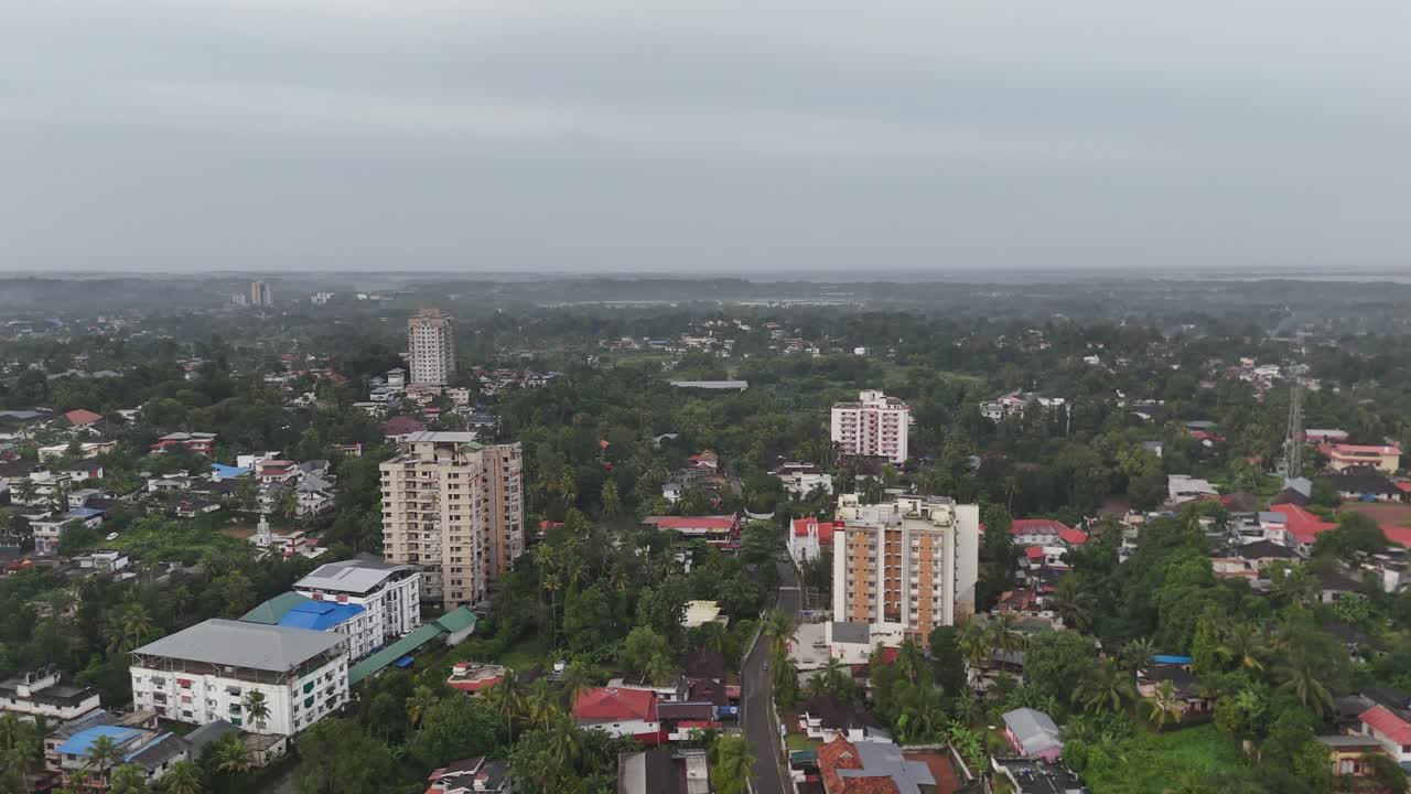 Elevata ripresa aerea di una piccola città del Kerala con vegetazione lussureggiante e spazi aperti visibili tra i nuclei residenziali