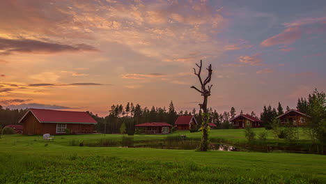 cabañas de madera rojas con estanque y pasto verde al atardecer