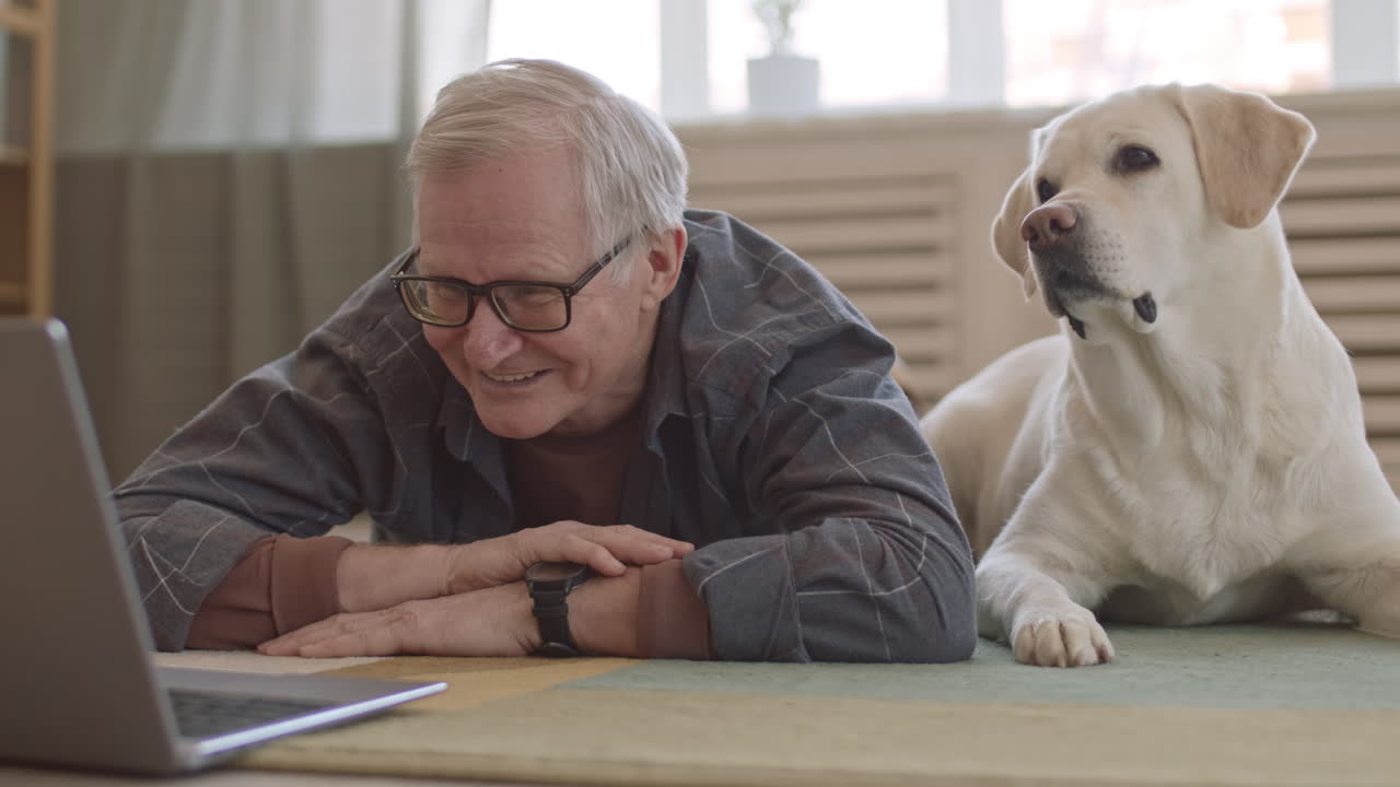 Senior Man and Dog Watching Funny Videos on Laptop