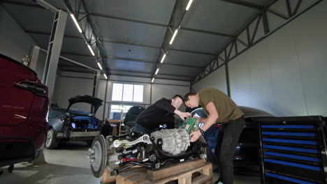 técnicos automotores que trabajan en un tren de transmisión de vehículos eléctricos en un garaje