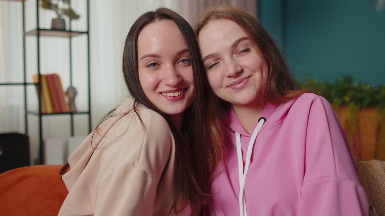 Close up portrait of happy attractive girls friends siblings embracing smiling looking at camera