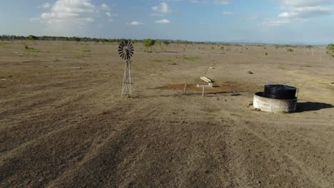 órbita aérea alrededor del antiguo molino de viento y tanque en campos desolados australianos