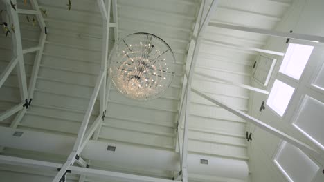 Slow orbiting shot of a chandelier hanging within a barn for a wedding