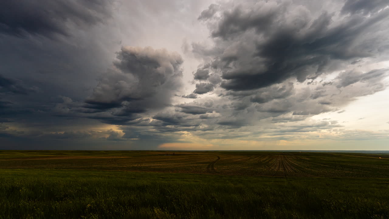 Dark clouds drift away as light fades in late evening time lapse