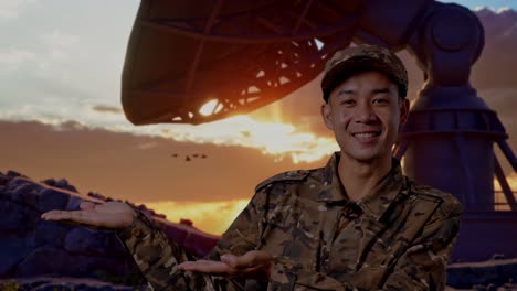close up of asian man soldier smiling and pointing to side while standing with satellite dish