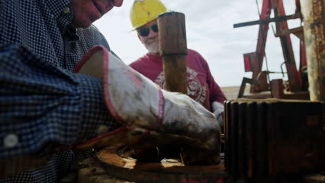 workers in helmets arrange the equipment for oil boring. man takes the spray bottle and covers the details.
