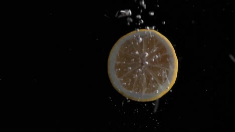 Lemon-Falling-into-Water-Super-Slowmotion,-Black-Background,-lots-of-Air-Bubbles,-4k240fps