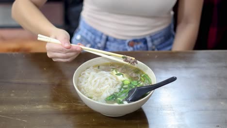 person enjoying vietnamese pho with chopsticks