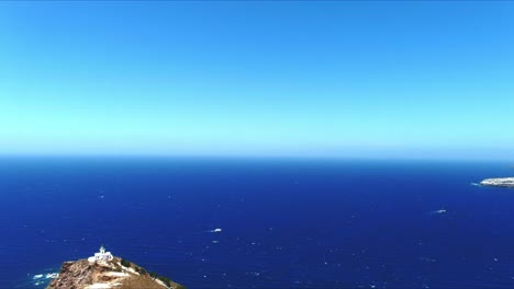 aerial 4k blue sea and sky top view over akrotiri lighthouse with wind turbulance in santorini greece