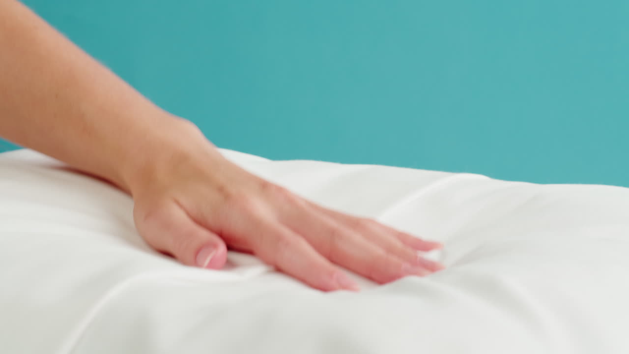 Hand touching a white pillow