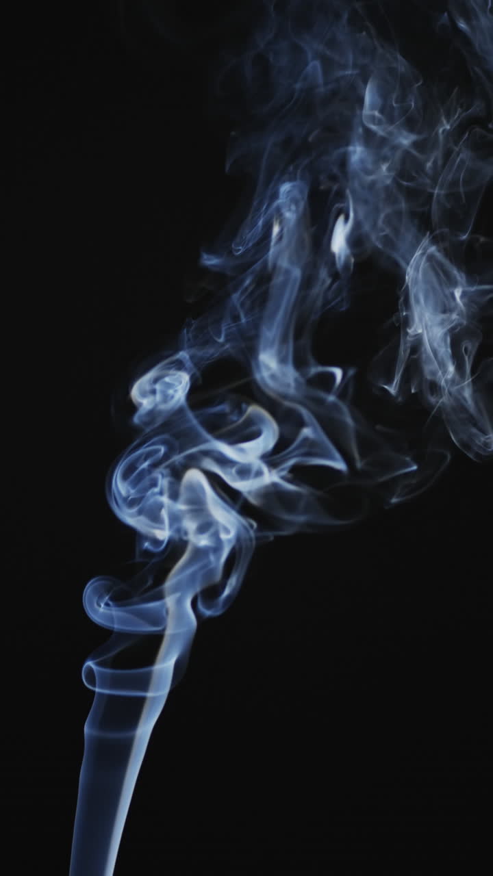 Vertical video of white clouds of smoke moving with copy space on black background