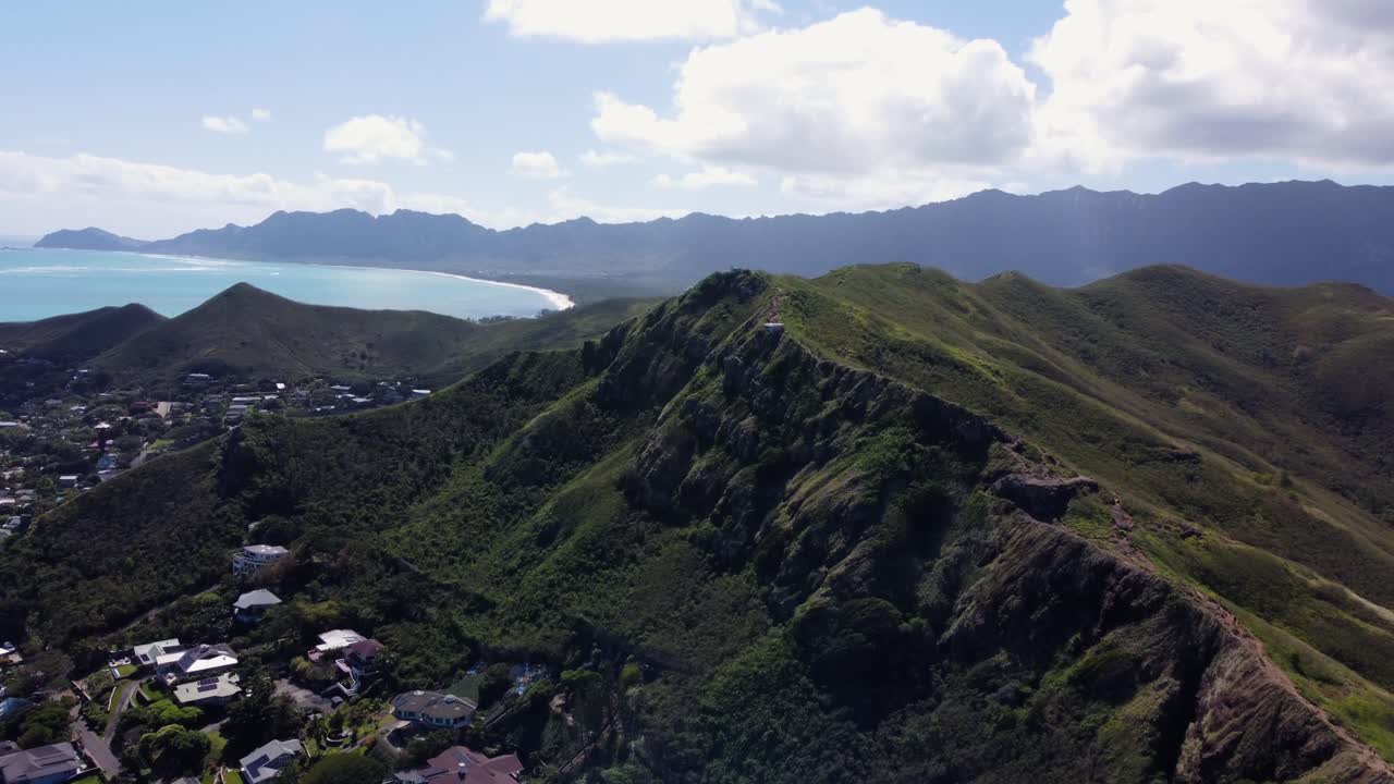 AERIAL Side Panning Shot of Coastal Ridges of Oahu, Hawaii with a Crescent Beach in the Background