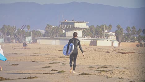 man in wetsuit holding surfboard