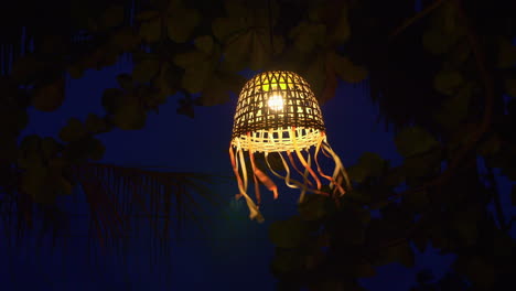 Woven-lantern-with-bright-light-at-night,-close-up