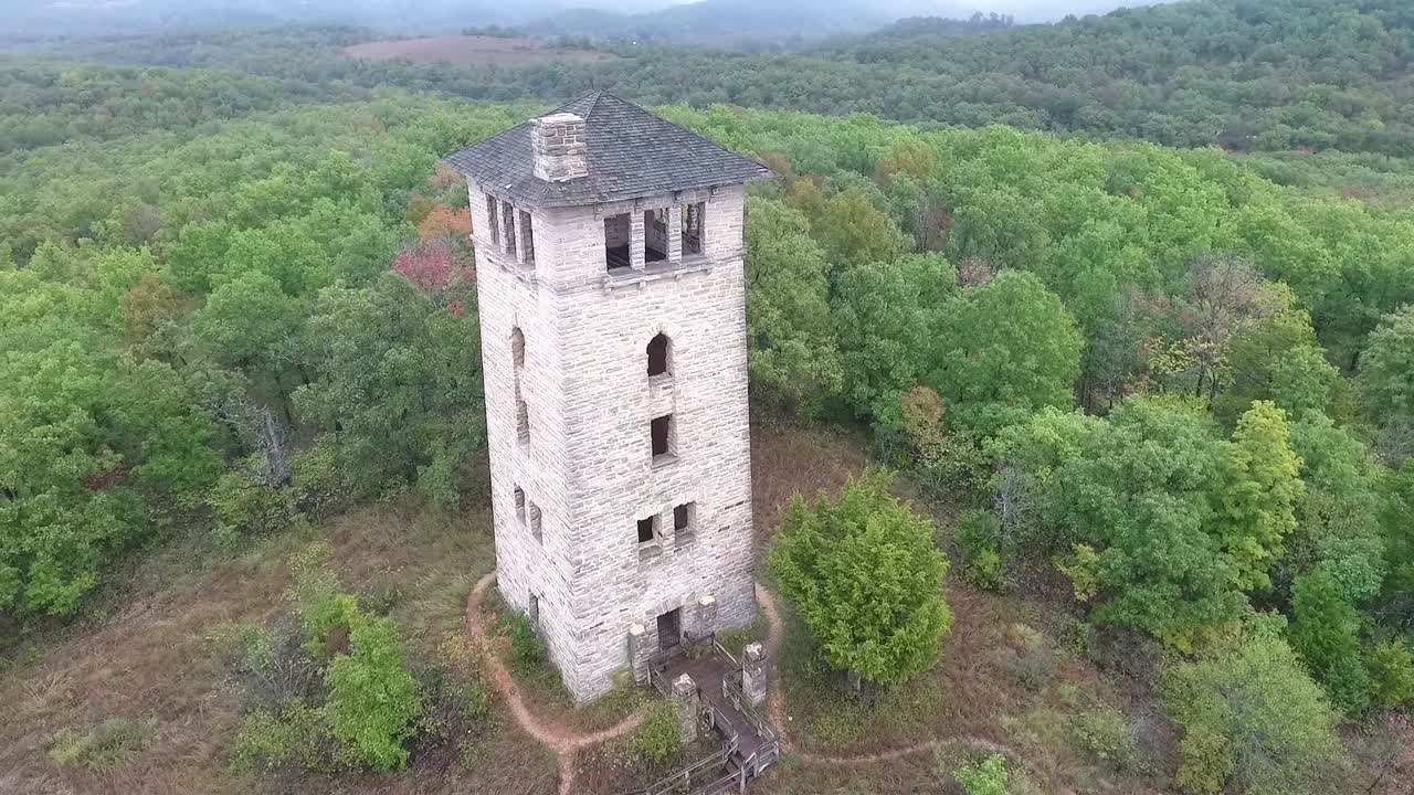 Drone doing a 60 degree rotation around watchtower at Haha Tonka state park with epic scenery of autumn colored trees and sky in background