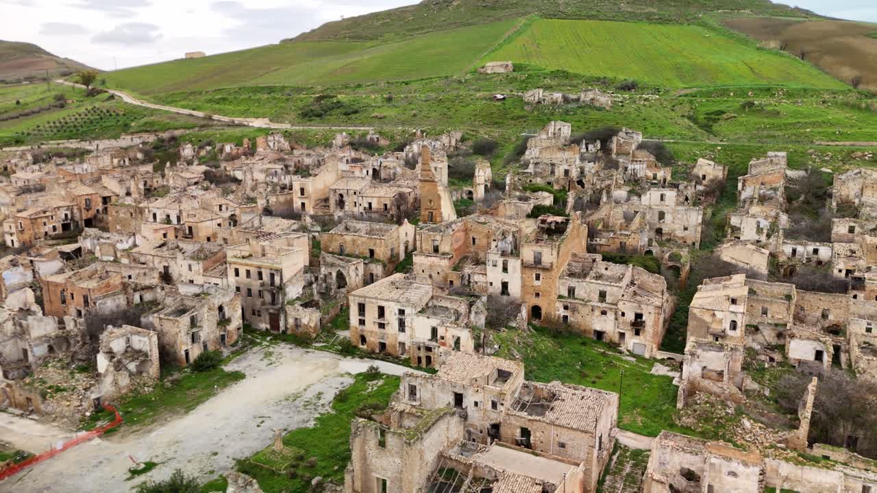 Etrafında yemyeşil tepelerin bulunduğu terk edilmiş bir köyün havadan görünümü