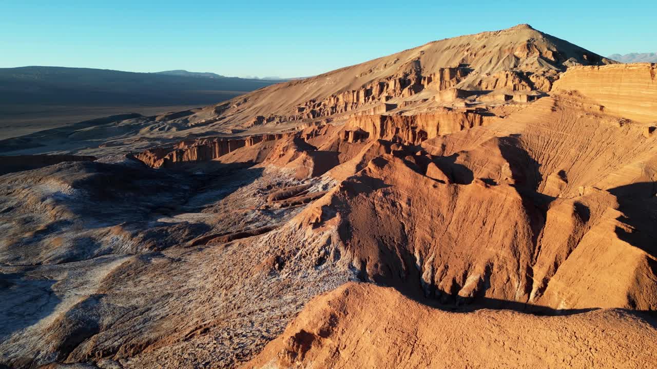 Majestic aerial sequence of rugged terrain and reflective flats glowing warmly in late-day desert light