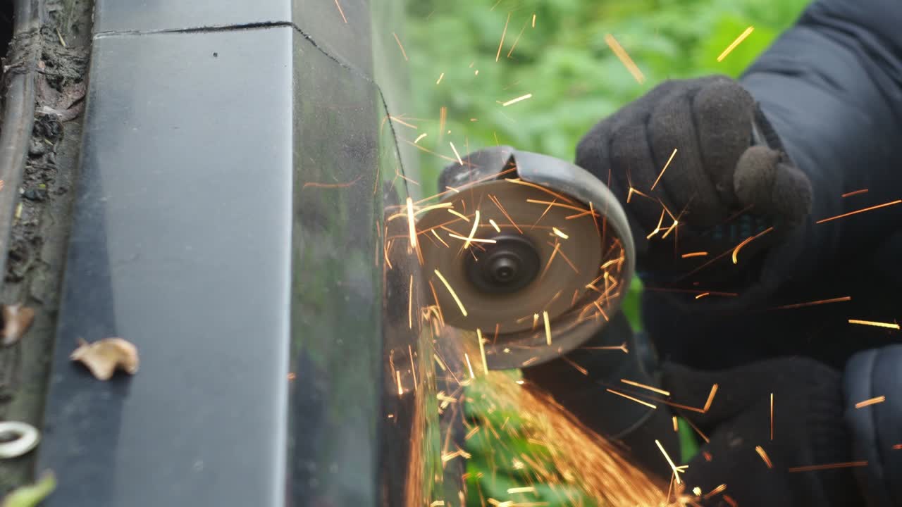 un hombre con guantes corta metal con un disco de corte. molinillo angular. trabajar con metal. salpicaduras brillantes ardientes del disco en todas direcciones. reparación de automóviles. mecánico de trabajos de ensamblaje mecánico