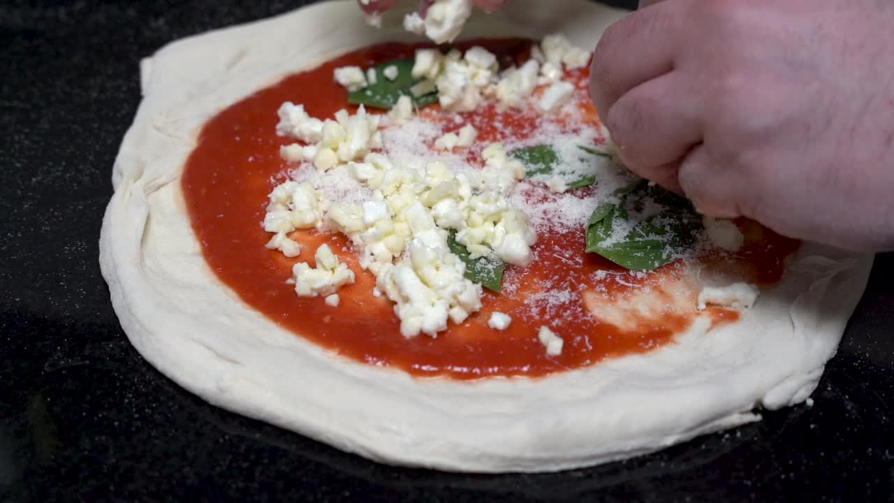 셰프가 느린 속도로 이탈리아 피자에 치즈를 넣고 있다