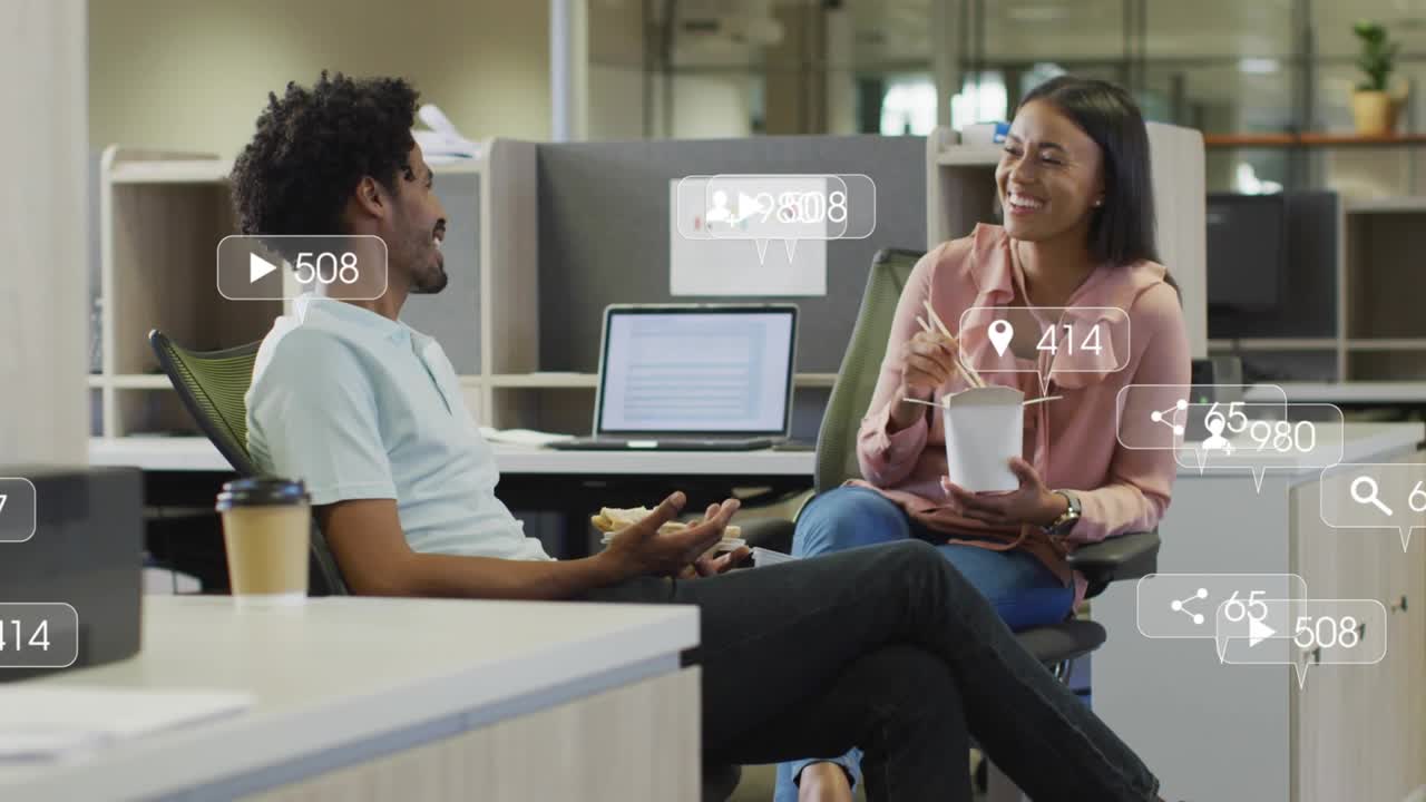 Man speaking and gesturing at shared desk, conversation spawning marketing icons over desk, laptop