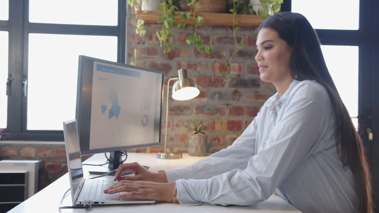 Working on computer, woman analyzing data on monitor in modern office