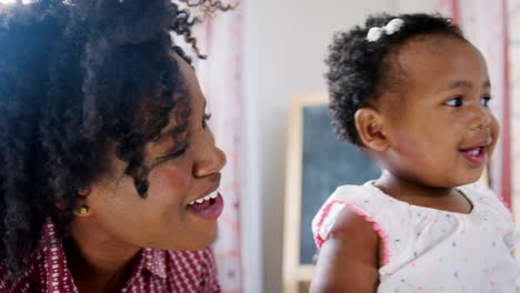 smiling mother cuddling baby daughter at home