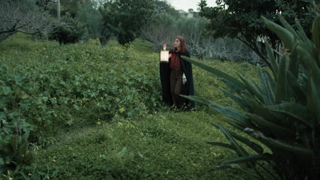 woman walks mysteriously among plants and trees of forest with a lantern