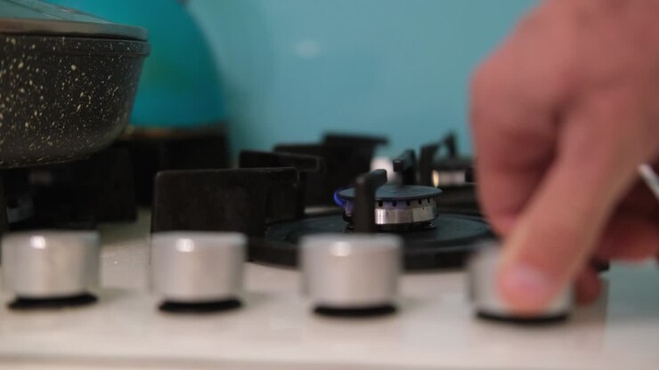 The hand turns on the gas burner on the kitchen stove. Gas does not burn well on a small comfort on the stove. The concept of gas consumption in Europe. Saving gas.