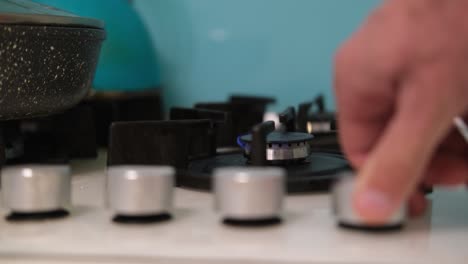 The hand turns on the gas burner on the kitchen stove. Gas does not burn well on a small comfort on the stove. The concept of gas consumption in Europe. Saving gas.