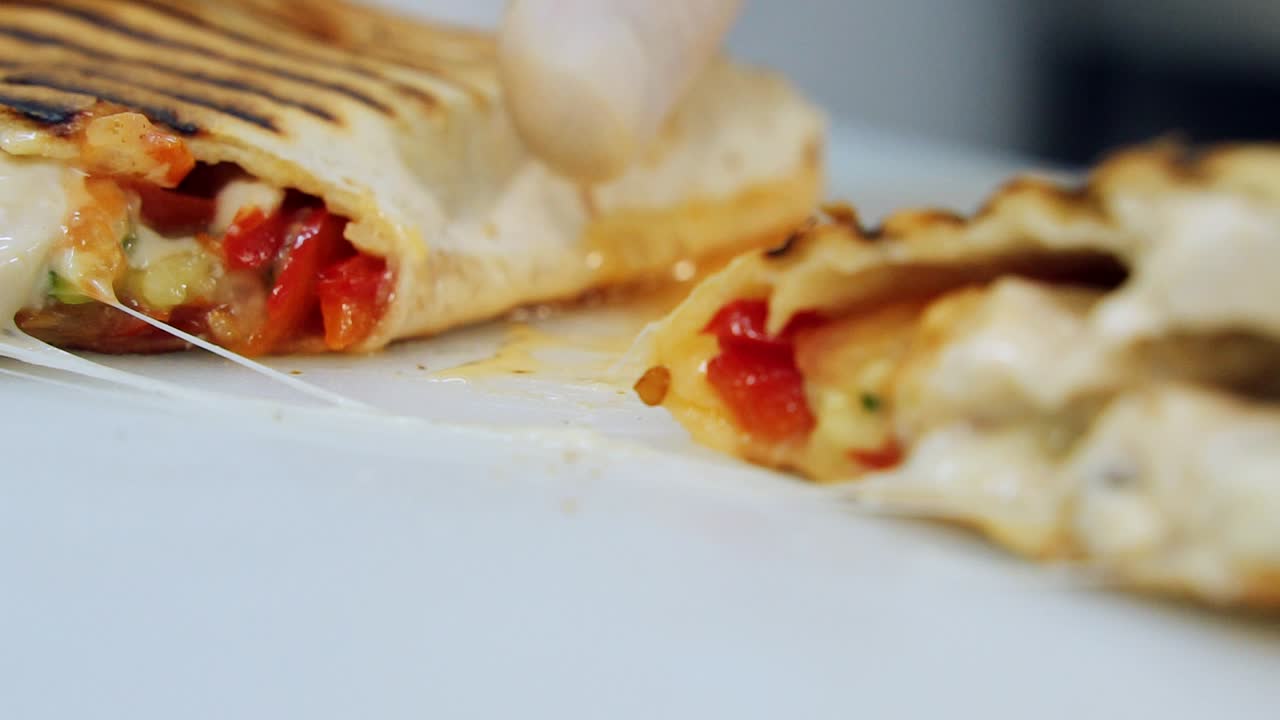 Mouth-watering roll with melted cheese. Delicious pita cutted into two pieces. Shawarma ready to eat. Food advertising concept. Close-up