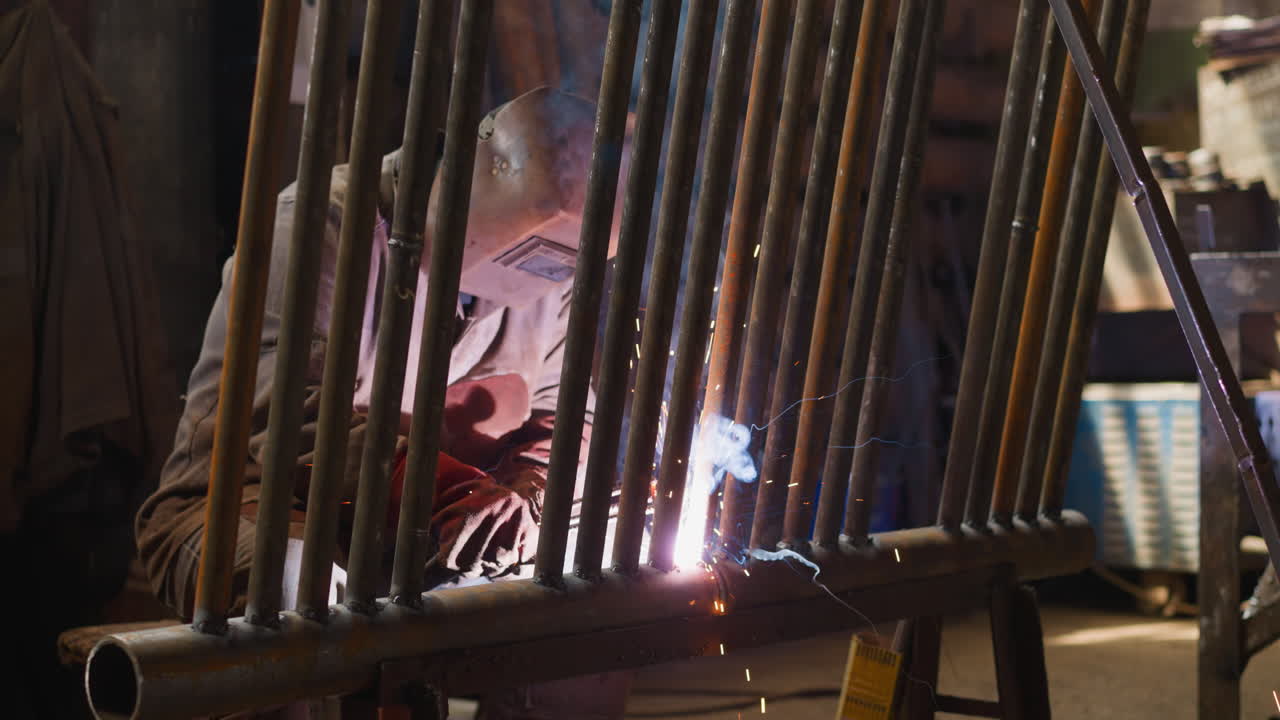 Torch worker in mask welds metal pipeline for boiler room