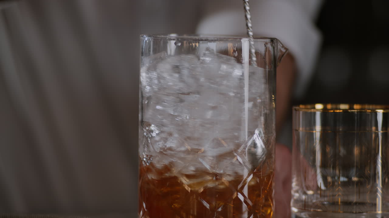 il barista agita un vecchio stile nel ghiaccio in un grande bicchiere di miscelazione
